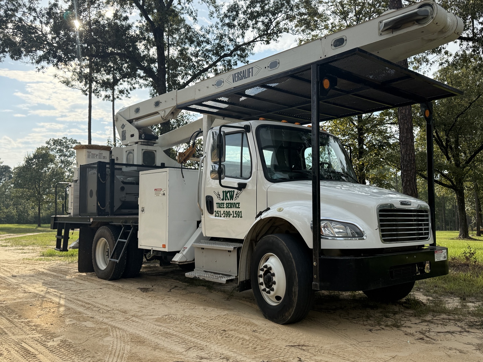 JKW Tree Service bucket truck on a wooded property